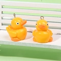Pair of yellow resin duck charms with silver metal rings on a white miniature bench - No.1 Duck With Eyelet / Yellow