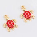 Primer plano de colgantes de tortuga con marco dorado y esmalte rojo de textura hexagonal - Tortuga marina