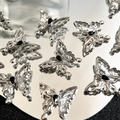 Macro shot of silver butterfly charms with black ink patterns and teardrop stones - Silver