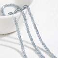 Strang aus facettierten 2mm graublauen Spinellperlen über einer weißen Porzellanschale - Ca. 230 Stück pro Strang / Graublau