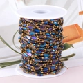 DIY jewelry chain with iridescent blue-purple beads and gold metal links on white spool - Gold-Peacock Blue Beads