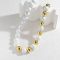 Luxurious iridescent white and gold faceted beaded necklace on a white display - Faceted Iridescent Round Bead Style (OLBN2257-yuan)