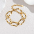 Détail du bracelet doré avec maillons ovales irréguliers sur une surface en pierre - Style B-Or (Bracelet)