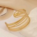 Detail shot of a golden multi-layer镂空 hammered cuff bracelet on white stone - Modern Geometric Intertwined Cable Style (1174) / 18K Gold