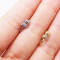 Close-up of gold and silver cow nose rings with white zircons on a finger - Cow / Steel