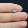 Macro shot of tiny silver flower cartilage stud with blue stones on a finger - Blue Gemstone Cluster Style (24080305050)