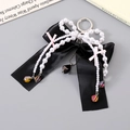 Détail d'un élégant nœud en soie noire avec chaînes de perles blanches et perles colorées - Noir