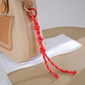 Detail eines handgefertigten Taschenanhängers aus rotem Nylonseil mit Metallring-Clip - Knopfknoten-Stil / Rot