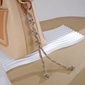 Detailansicht einer beigen Ledertasche mit handgewebten Nylonknoten und feinen Nähten - Knopfknoten-Stil / Khaki