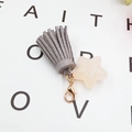 Macro shot of grey suede tassel with creamy star charm and golden lobster clasp - Grey with White Star