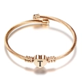 Detail van roségouden gedraaide kabelarmband met een gegraveerd hart en de letter T - Initiaal T