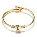 Detail van 18K gouden gedraaide kabelarmband met hartvormige hanger en gegraveerde letter L - L
