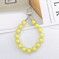 Detailed macro view of acrylic candy-colored beaded pendant with silver metal hook clasp - Bead-in-Bead Pendant / Yellow