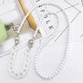 Close-up of white beaded and curb chain phone strap with heart-shaped ring on Kinfolk magazine - White