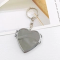 Porte-clés médaillon en forme de cœur argenté poli avec miroir pliant sur fond blanc - K674 Miroir Coeur Pliant