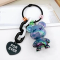 Macro detail of iridescent bear keychain with X-eyes, chunky chain and black heart charm - Gray
