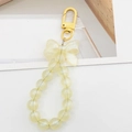 Detail of yellow beaded keychain featuring a matte bow and translucent resin beads - Yellow
