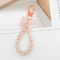 Detailed view of champagne pink beaded keychain featuring a matte ribbon bow charm - Orange