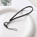 Gros plan sur cordon de téléphone en cuir tressé noir avec clip métallique sur plateau - Wristlet - Black