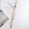 Détail d'accessoire chaîne en acrylique crème avec métal doré et perle marbrée sur revue - Chaîne à main / Beige