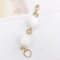 Detail of plush faux fur charms with gold heart pendants and magnetic jewelry clasps - White