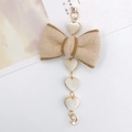 Detail of a beige felt bow keychain with white velvet heart pendants and gold metal clasp - Off White