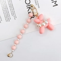 Close-up of pink matte balloon dog charm with faux pearl collar and gold keychain hardware - Pink