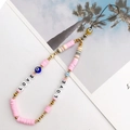 Dettaglio di perline rosa, distanziatori dorati e malocchio su cinturino boho per cellulare - K802 Malocchio + argilla morbida rosa