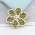 Close-up of alloy flower brooch with green rhinestones and white pearls on gold base - Green Pearl Flower (D1405)