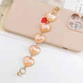 Detail of beaded heart-shaped accessory strap with golden edges on a pink phone case - Colorful Orange