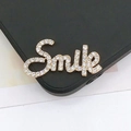 Detalle macro del colgante Smile con circonitas brillantes sobre base dorada - Letras con Diamantes (D1450)