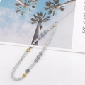 Dettaglio macro del cinturino per cellulare fatto a mano con perline blu e fiori dorati - Grigio
