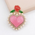 Gros plan d'un charme cœur rose avec perles blanches et détail de rose rouge élégante - Rose