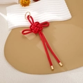 Detalle de nudo chino rojo artesanal con anillo de metal dorado sobre soporte de exhibición - Estilo de Cuero PU (K5989)