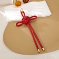 Detalle macro de nudo chino trenzado rojo con elegante anillo y puntas de metal dorado - Estilo de Cuero con Patrón (K5988)