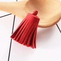 Close-up of 3cm red faux suede tassel with semi-circular ring on a wooden prop - Red