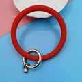Detalle de llavero de pulsera de silicona roja con cierre plateado sobre fondo pastel - Clásico / Rojo