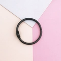 Detalle de una anilla de metal negra para encuadernación DIY sobre fondo geométrico pastel - Anillas de hojas sueltas / Negro