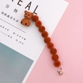 Detalle de un oso flocado marrón con cuentas naranjas y cierre de anillo metálico - Naranja