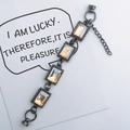 Detail view of gunmetal bracelet with four amber crystals on a white display card - Champagne (K188)