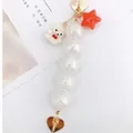 Detail of beaded bear pendant featuring white crackle beads and golden heart charms - White