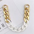 Macro-opname van matgouden metalen en witte acryl schakels met ronde veersluitingen - Handketting / Witte Handketting (K516ē½č²ęęé¾)