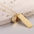 Minimalistische gouden rvs ketting met staaf en schijf hangers op steen - Goud