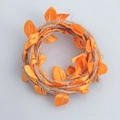 Close-up of handmade jute twine garland with decorative orange satin leaves for DIY - Orange
