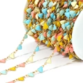 Golden DIY jewelry chain featuring multi-color heart-shaped enamel charms on a spool - Colorful