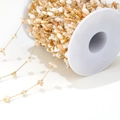 Macro detail of natural shell beads on gold plated DIY jewelry chain wound on a spool - 1mm Gold Chain / Cream Yellow Shell Link