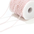 Detailed macro of pink faceted crystal beads with golden chain on a white spool - Light Pink
