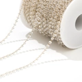 Macro detail of transparent crystal beads on a golden chain wound on a white spool - Clear