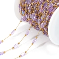 DIY jewelry chain with faceted purple glass beads and golden links on white spool - Purple