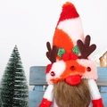 Christmas gnome plush with striped hat, reindeer antlers and long beard on wooden background - Red